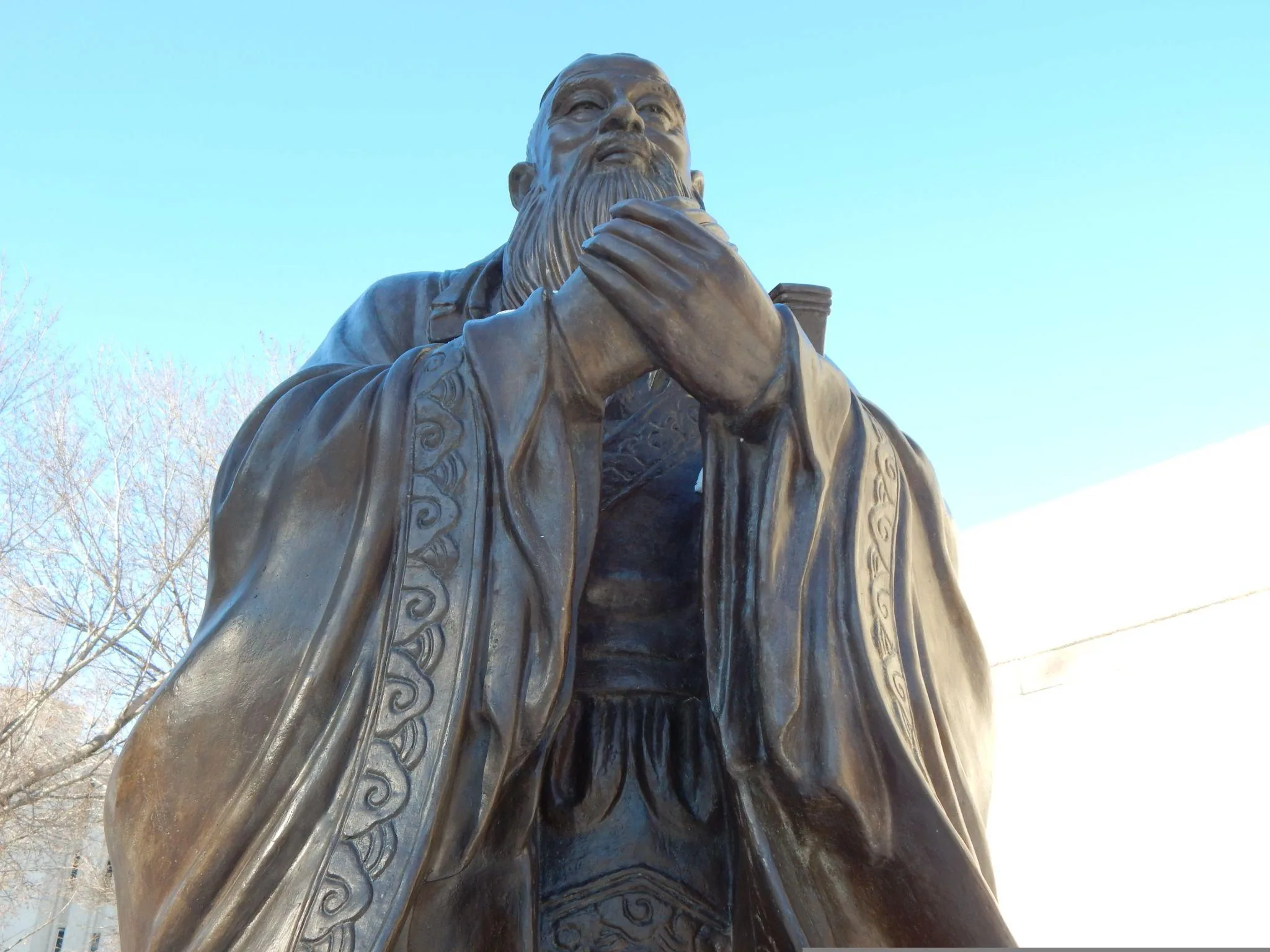 Bronze statue of Confucius against a clear sky